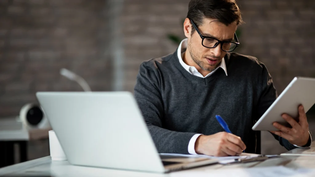 Contador da Komcorp organizando documentos para a declaração do Imposto de Renda 2026 em um escritório moderno.